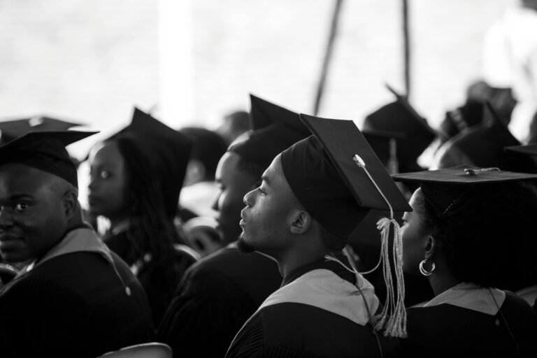 A group of students in graduation gowns and mortarboards attending a ceremony.